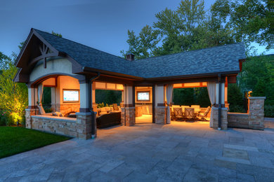 Mid-sized traditional backyard patio in Chicago with natural stone pavers and a roof extension.