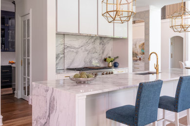 Example of a transitional l-shaped medium tone wood floor and brown floor kitchen design in Dallas with an undermount sink, shaker cabinets, white cabinets, an island and gray countertops