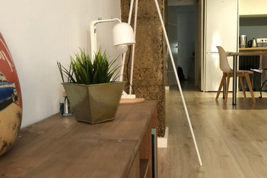 Immagine di un soggiorno design con pareti bianche, pavimento in laminato, pavimento marrone e pareti in mattoni