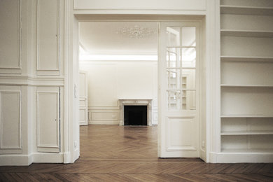 Idée de décoration pour une grande salle de séjour tradition fermée avec un mur blanc, parquet foncé, une cheminée standard et un manteau de cheminée en pierre.