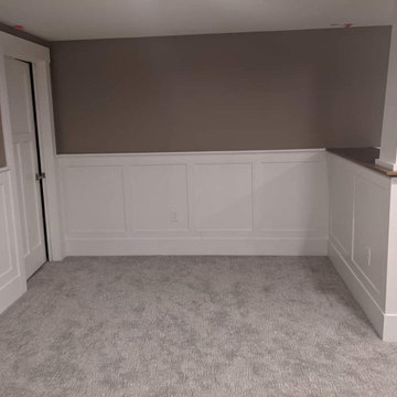Basement with a banquette, beams, wainscot and bookcases