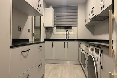 Modelo de cocina alargada, abovedada y gris y negra minimalista de tamaño medio cerrada y de obra sin isla con fregadero de doble seno, armarios con paneles empotrados, con blanco y negro, encimera de mármol, salpicadero verde, salpicadero de mármol, electrodomésticos negros, suelo de madera clara, suelo beige y encimeras negras