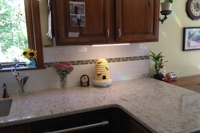 Example of a transitional kitchen design in Boston with an undermount sink, raised-panel cabinets, dark wood cabinets, granite countertops, white backsplash, subway tile backsplash, stainless steel appliances and a peninsula