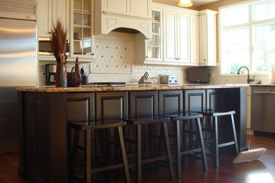 Mid-sized elegant l-shaped dark wood floor and brown floor eat-in kitchen photo in Chicago with raised-panel cabinets, white cabinets, granite countertops, white backsplash, subway tile backsplash, stainless steel appliances and an island