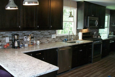 Enclosed kitchen - mid-sized transitional l-shaped porcelain tile and brown floor enclosed kitchen idea in Baltimore with an undermount sink, shaker cabinets, dark wood cabinets, granite countertops, multicolored backsplash, glass tile backsplash, stainless steel appliances, a peninsula and gray countertops