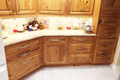 This is an example of a country eat-in kitchen in Denver with raised-panel cabinets, medium wood cabinets, beige splashback, ceramic floors and no island.