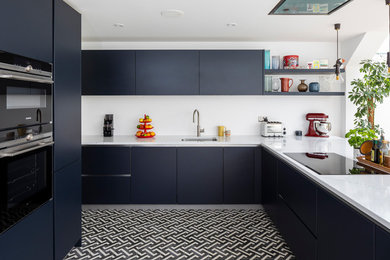 Photo of a contemporary kitchen in London with a single-bowl sink, solid surface benchtops and black appliances.