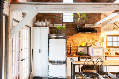 Small mountain style kitchen photo in Other with wood countertops and brick backsplash