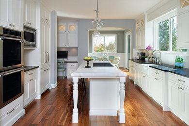 Mid-sized elegant u-shaped dark wood floor open concept kitchen photo in Denver with a farmhouse sink, shaker cabinets, white cabinets, quartz countertops, white backsplash, subway tile backsplash, paneled appliances and an island