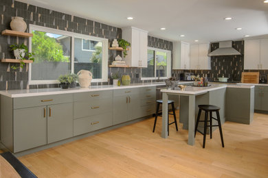 Inspiration for a mid-sized contemporary l-shaped light wood floor and beige floor eat-in kitchen remodel in San Francisco with an undermount sink, shaker cabinets, green cabinets, quartz countertops, multicolored backsplash, porcelain backsplash, stainless steel appliances, an island and white countertops