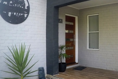 Photo of a mid-sized contemporary one-storey brick grey house exterior in Other with a metal roof.