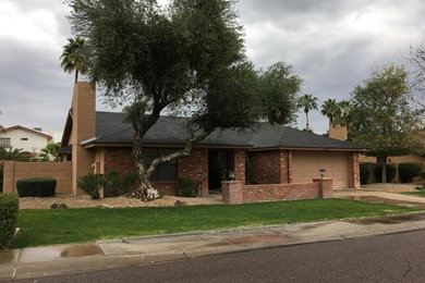 Example of a mid-sized minimalist red one-story brick house exterior design in Phoenix with a clipped gable roof and a shingle roof