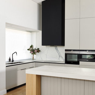 Inspiration for a large contemporary l-shaped eat-in kitchen in Perth with a double-bowl sink, flat-panel cabinets, grey cabinets, quartz benchtops, white splashback, porcelain splashback, black appliances, light hardwood floors, with island, beige floor, white benchtop and vaulted.