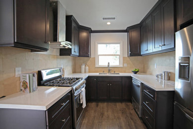 Mid-sized trendy u-shaped laminate floor and brown floor eat-in kitchen photo with a double-bowl sink, shaker cabinets, dark wood cabinets, quartzite countertops, multicolored backsplash, travertine backsplash, stainless steel appliances, no island and white countertops