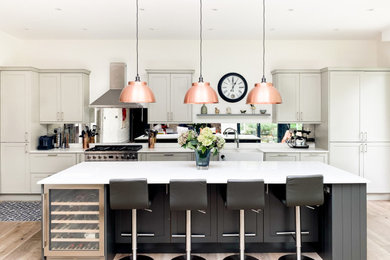 Example of a large trendy l-shaped medium tone wood floor and brown floor open concept kitchen design in London with an undermount sink, shaker cabinets, gray cabinets, marble countertops, metallic backsplash, glass sheet backsplash, stainless steel appliances, an island and white countertops