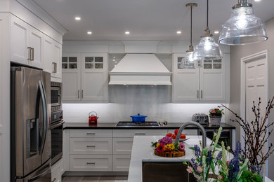 Example of a mid-sized transitional l-shaped porcelain tile and gray floor eat-in kitchen design in Toronto with an undermount sink, shaker cabinets, white cabinets, quartz countertops, white backsplash, porcelain backsplash, stainless steel appliances, an island and multicolored countertops