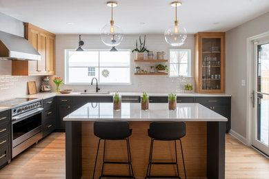 Inspiration for a mid-sized transitional l-shaped light wood floor kitchen remodel in Minneapolis with an undermount sink, flat-panel cabinets, medium tone wood cabinets, solid surface countertops, white backsplash, ceramic backsplash, stainless steel appliances, an island and white countertops