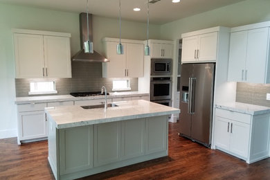 Example of a mid-sized transitional l-shaped brown floor eat-in kitchen design in Dallas with a double-bowl sink, shaker cabinets, white cabinets, stainless steel appliances and an island