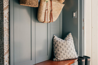 Inspiration for a small timeless porcelain tile, gray floor and wallpaper laundry room remodel in Los Angeles with a farmhouse sink, shaker cabinets, blue cabinets, marble countertops, white backsplash, ceramic backsplash and a stacked washer/dryer