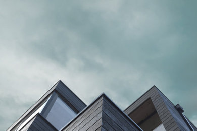 Ejemplo de fachada de casa negra y negra minimalista de tamaño medio de tres plantas con revestimientos combinados, tejado plano, tejado de teja de madera y panel y listón
