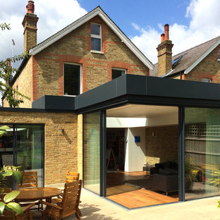 Exempel på ett modernt gult radhus, med tegel