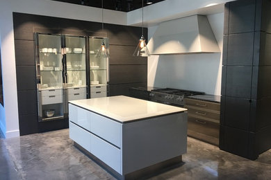 Mid-sized minimalist l-shaped concrete floor and brown floor open concept kitchen photo in Charlotte with flat-panel cabinets, brown cabinets, quartz countertops, stainless steel appliances, an island and white countertops