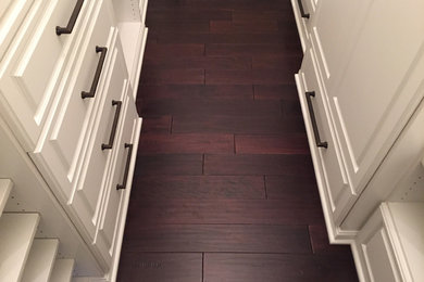 Example of a small transitional gender-neutral dark wood floor walk-in closet design in Cincinnati with raised-panel cabinets and white cabinets