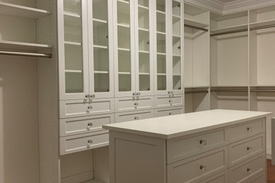 Example of a large classic gender-neutral walk-in closet design in New York with shaker cabinets and white cabinets
