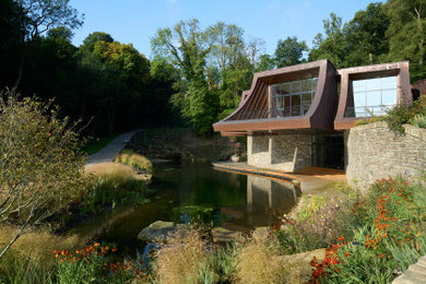 Photo of an expansive contemporary partial sun garden for summer in Other with a pond and decking.