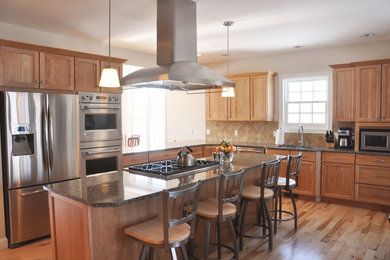 Example of a large transitional l-shaped light wood floor open concept kitchen design in Burlington with an undermount sink, recessed-panel cabinets, medium tone wood cabinets, granite countertops, beige backsplash, stone tile backsplash, stainless steel appliances and an island