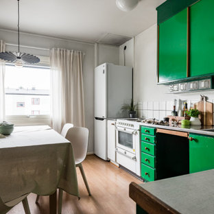 Foto på ett skandinaviskt grå kök, med en integrerad diskho, släta luckor, gröna skåp, bänkskiva i rostfritt stål, vitt stänkskydd, vita vitvaror, mellanmörkt trägolv och brunt golv