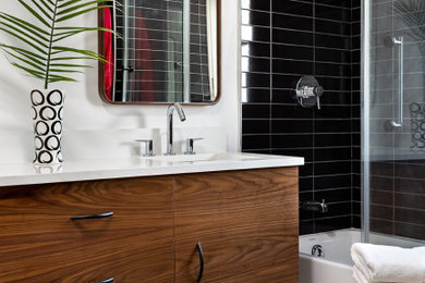 Mid-sized mid-century modern black tile and subway tile ceramic tile, white floor and double-sink bathroom photo in Dallas with flat-panel cabinets, medium tone wood cabinets, a two-piece toilet, white walls, an undermount sink, solid surface countertops, white countertops and a floating vanity
