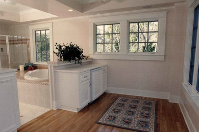 Example of a classic beige tile and ceramic tile light wood floor bathroom design in Other with flat-panel cabinets, white cabinets, beige walls and granite countertops