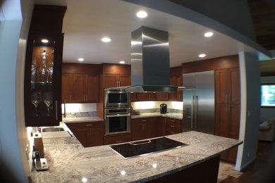 Large contemporary u-shaped kitchen in Hawaii with shaker cabinets, dark wood cabinets, granite worktops, stainless steel appliances, ceramic flooring and an island.