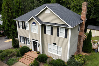 Diseño de fachada de casa beige y negra tradicional de tamaño medio de dos plantas con revestimiento de vinilo y tejado de teja de madera
