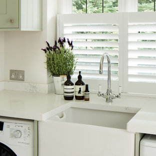 ロンドンのカントリー風おしゃれなランドリールーム (エプロンフロントシンク、シェーカースタイル扉のキャビネット、人工大理石カウンター、左右配置の洗濯機・乾燥機) の写真