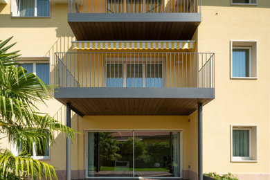 Esempio della facciata di una casa bifamiliare gialla contemporanea a tre piani con rivestimenti misti