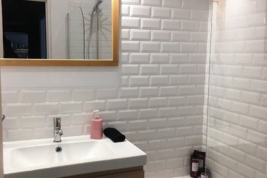 Cette image montre une petite salle de bain principale nordique en bois clair avec un placard à porte affleurante, une baignoire encastrée, un carrelage blanc, un carrelage métro, un mur blanc, carreaux de ciment au sol, un plan vasque, un plan de toilette en marbre, un sol multicolore et un plan de toilette blanc.