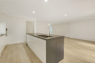 Design ideas for a modern galley open plan kitchen in Other with a double-bowl sink, white cabinets, white splashback, ceramic splashback, with island, grey floor, grey benchtop and laminate benchtops.