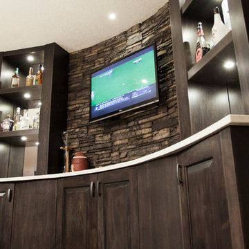 Stone basement wetbar and dark wood cabinetry