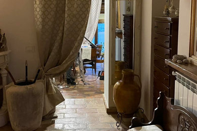 他の地域にある中くらいなカントリー風のおしゃれな玄関ロビー (ベージュの壁、ライムストーンの床、茶色いドア、ベージュの床、格子天井) の写真