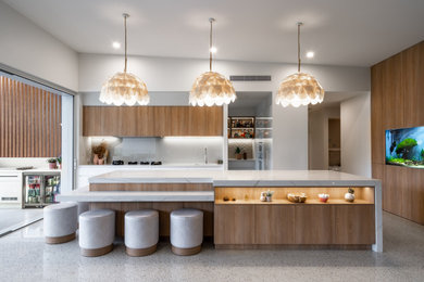 Cette photo montre une cuisine parallèle tendance en bois brun avec un placard à porte plane, une crédence grise, îlot, un sol gris, un plan de travail blanc, un plafond voûté et un évier encastré.