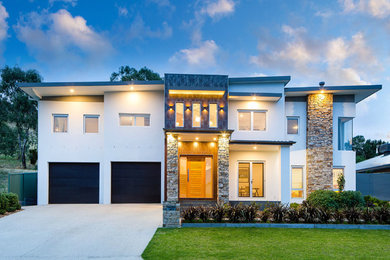 Design ideas for a large contemporary two-storey white exterior in Sydney with stone veneer and a flat roof.