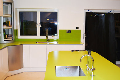 Große Moderne Wohnküche ohne Insel mit Glas-Arbeitsplatte, Küchenrückwand in Grün und Glasrückwand in Hertfordshire