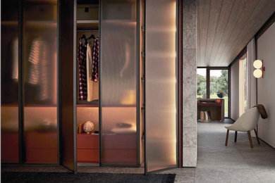 Imagen de armario vestidor de mujer minimalista grande con armarios tipo vitrina, puertas de armario de madera clara, suelo de baldosas de porcelana y suelo gris