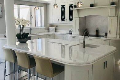 Inspiration for a large contemporary open plan kitchen in Hertfordshire with a drop-in sink, shaker cabinets, white cabinets, quartzite benchtops, white splashback, stone slab splashback, panelled appliances, porcelain floors, with island, white floor and white benchtop.