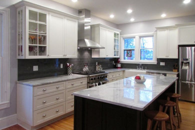 Mid-sized trendy u-shaped medium tone wood floor open concept kitchen photo in New York with a farmhouse sink, recessed-panel cabinets, white cabinets, marble countertops, gray backsplash, subway tile backsplash, stainless steel appliances and an island
