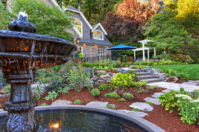 This is an example of a large traditional drought-tolerant and full sun front yard concrete paver and metal fence water fountain landscape in Portland.