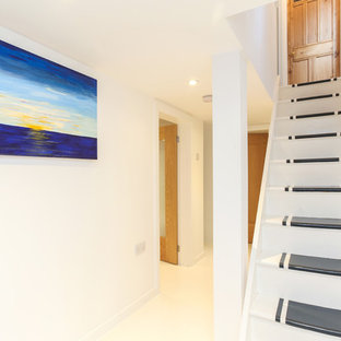 This is an example of a medium sized contemporary look-out basement in Manchester with white walls and painted wood flooring.