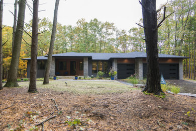 Réalisation d'une façade de maison grise en planches et couvre-joints de plain-pied avec un revêtement mixte, un toit à quatre pans, un toit en shingle et un toit noir.